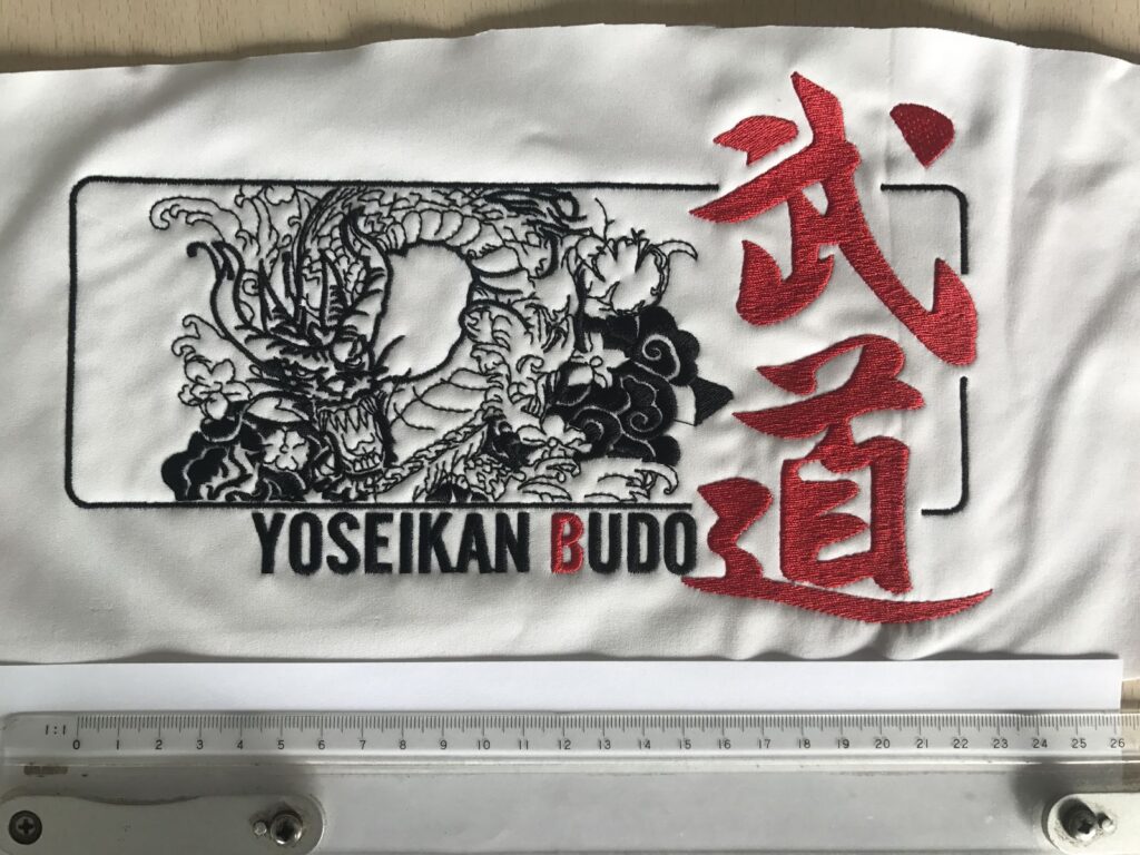 Rendu broderie d'un visuel dragon Yoseikan Budo photographié avec une règle graduée à l'échelle réelle